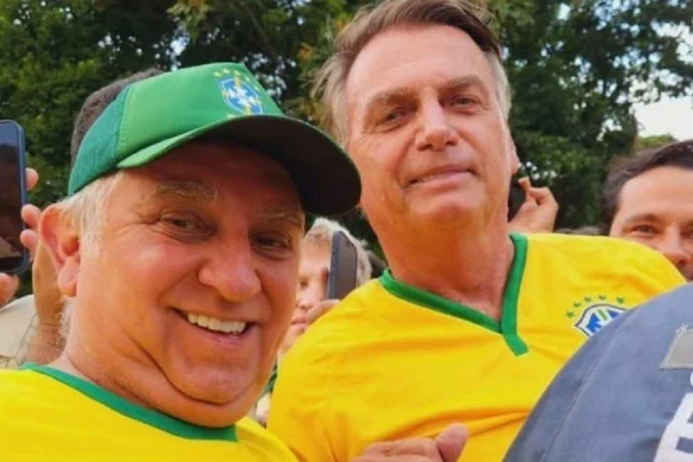 O senador Izalci Lucas (PL) e o ex-presidente Jair Bolsonaro (PL) sorrindo para selfie, lado a lado, com camisetas amarelas e verdes, o senador de boné