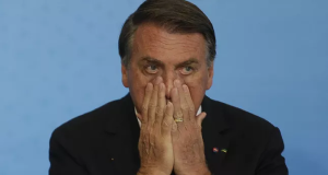 Jair Bolsonaro (PL) com as mãos no rosto, com expressão de medo
