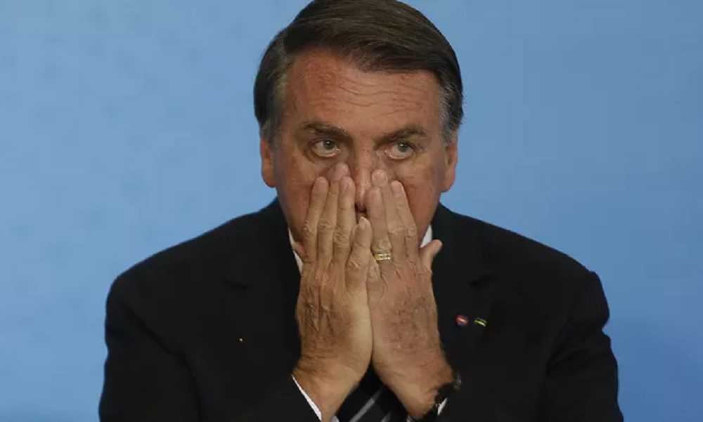 Jair Bolsonaro (PL) com as mãos no rosto, com expressão de medo