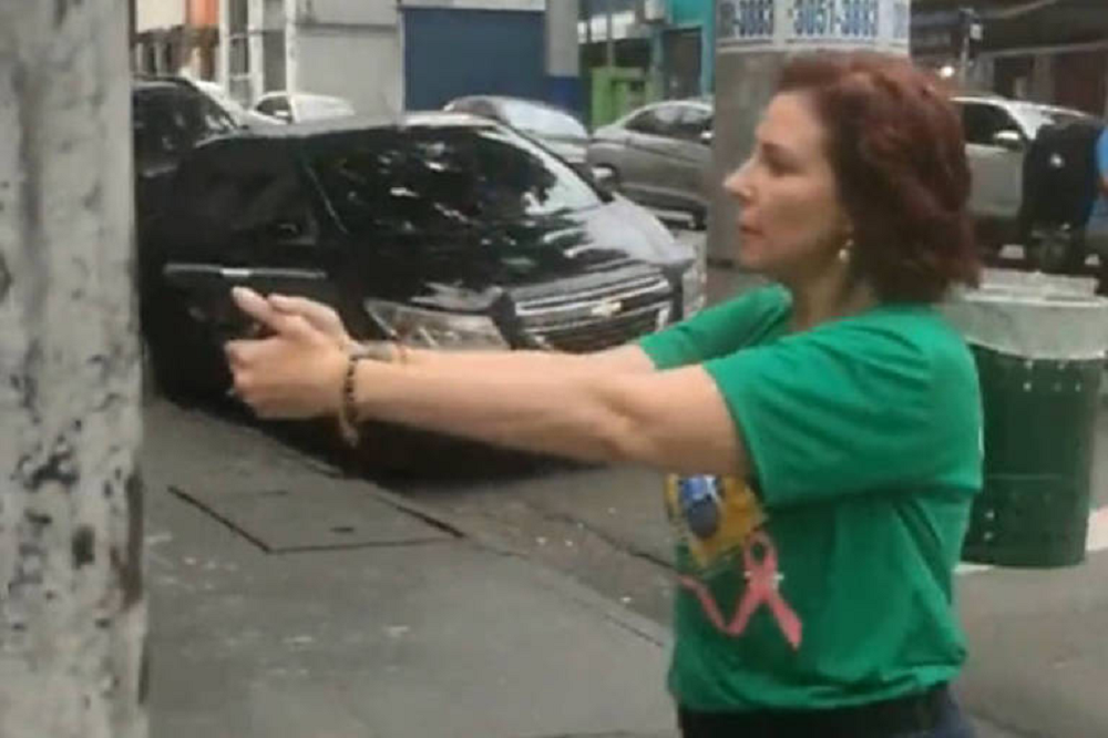 deputada Carla Zambelli (PL-SP) com arma em punho, de perfil, com camisa verde
