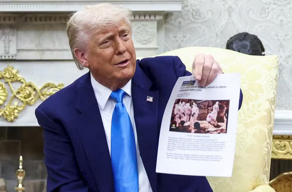 Donald Trump segurando imagem do Congo afirmando que se trata de ação na África do Sul, falando, sem olhar para a câmera