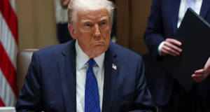 Donald Trump assinando papel com expressão triste