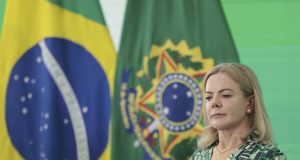 ministra Gleisi Hoffmann de vestido estampado, sentada, com expressão pensativa