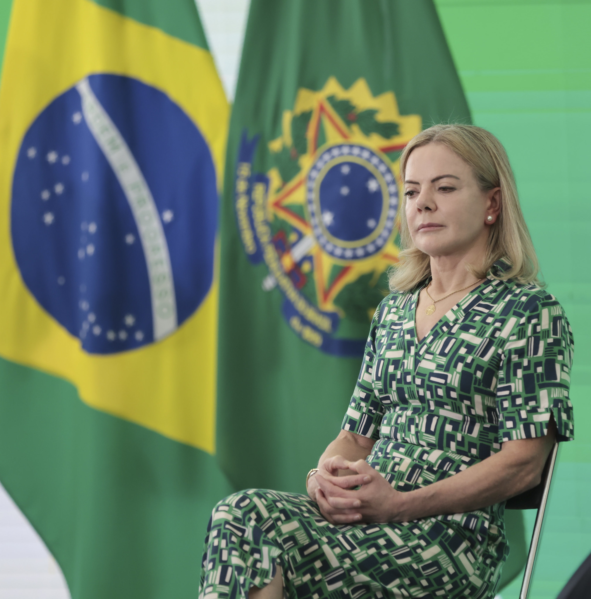 ministra Gleisi Hoffmann de vestido estampado, sentada, com expressão pensativa