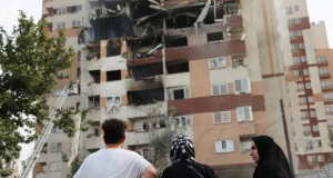 Pessoas observando prédio destruído por ataque em Teerã, no Irã
