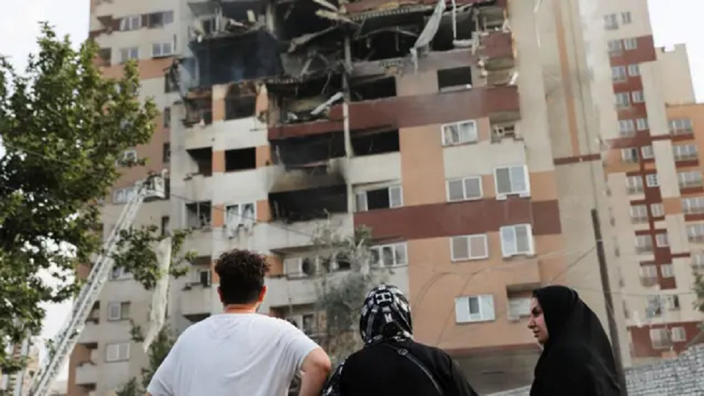 Pessoas observando prédio destruído por ataque em Teerã, no Irã
