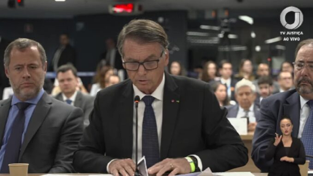 O ex-presidente Jair Bolsonaro (PL) de cabeça baixa e óculos, falando