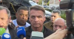 Jair Bolsonaro com expressão séria, sem olhar para a câmera, cercado de pessoas