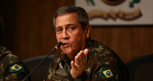 ex-ministro Walter Braga Netto fardado, falando em microfone, olhando e apontando para o lado