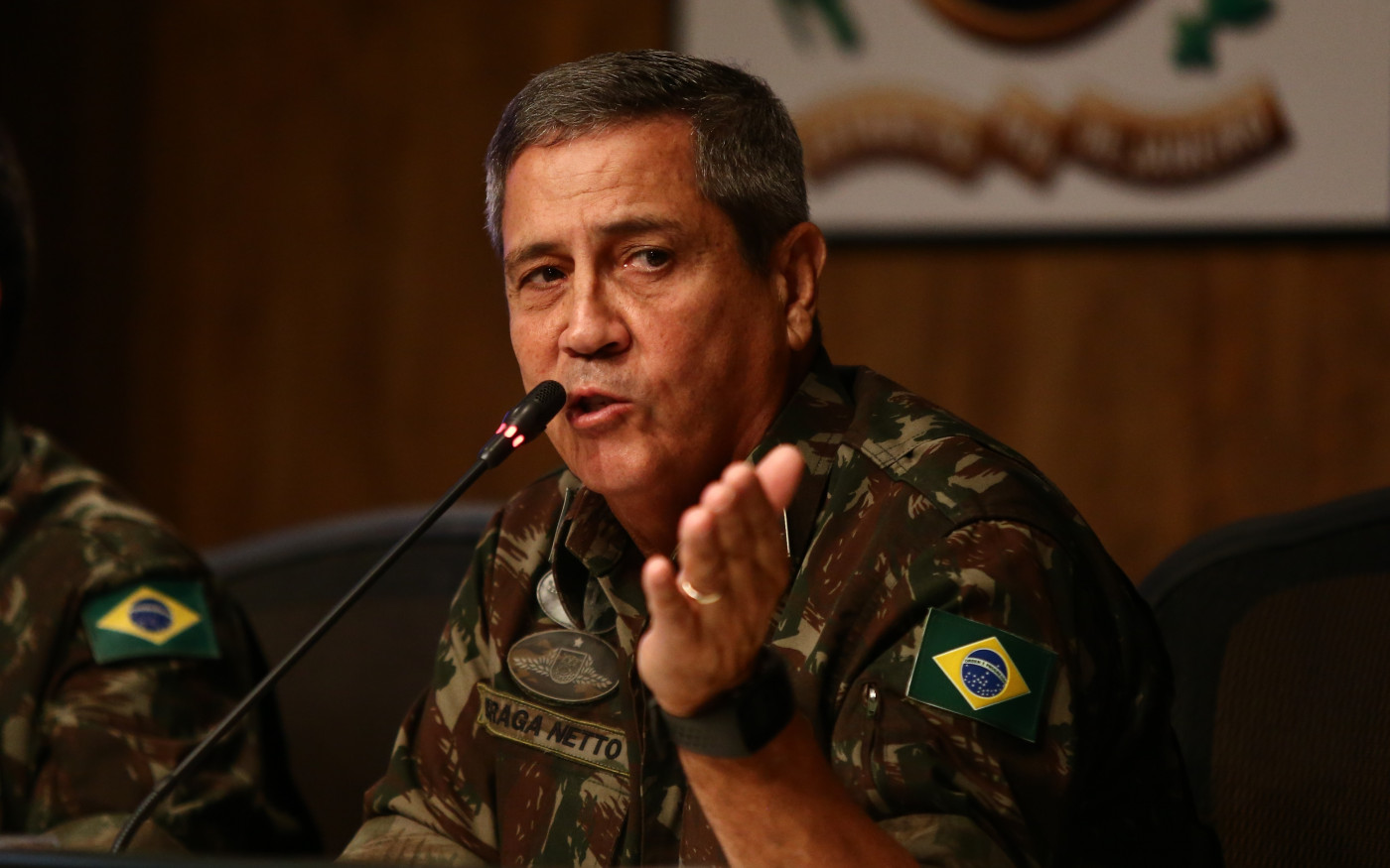 ex-ministro Walter Braga Netto fardado, falando em microfone, olhando e apontando para o lado