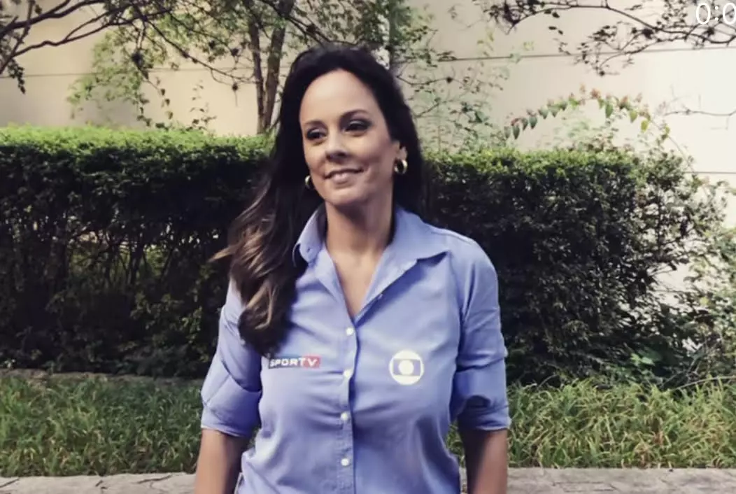A jornalista Fabíola Andrade sorrindo, de cabelo solto, com uniforme do SporTV