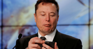 magnata Elon Musk olhando para o celular, sério