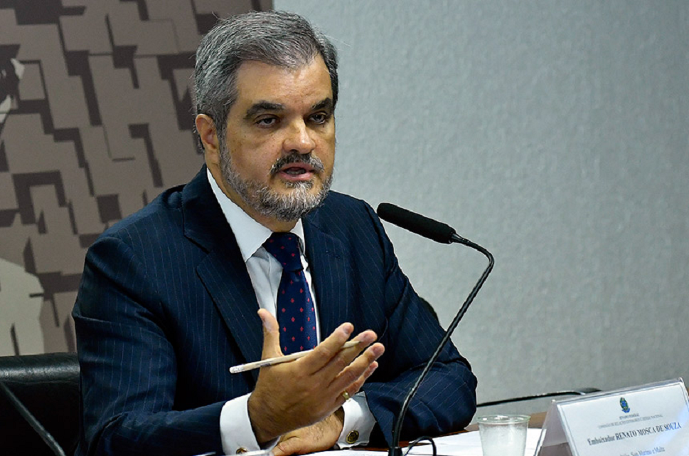 embaixador do Brasil na Itália, Renato Mosca, falando em microfone e gesticulando, sério, sem olhar para a câmera