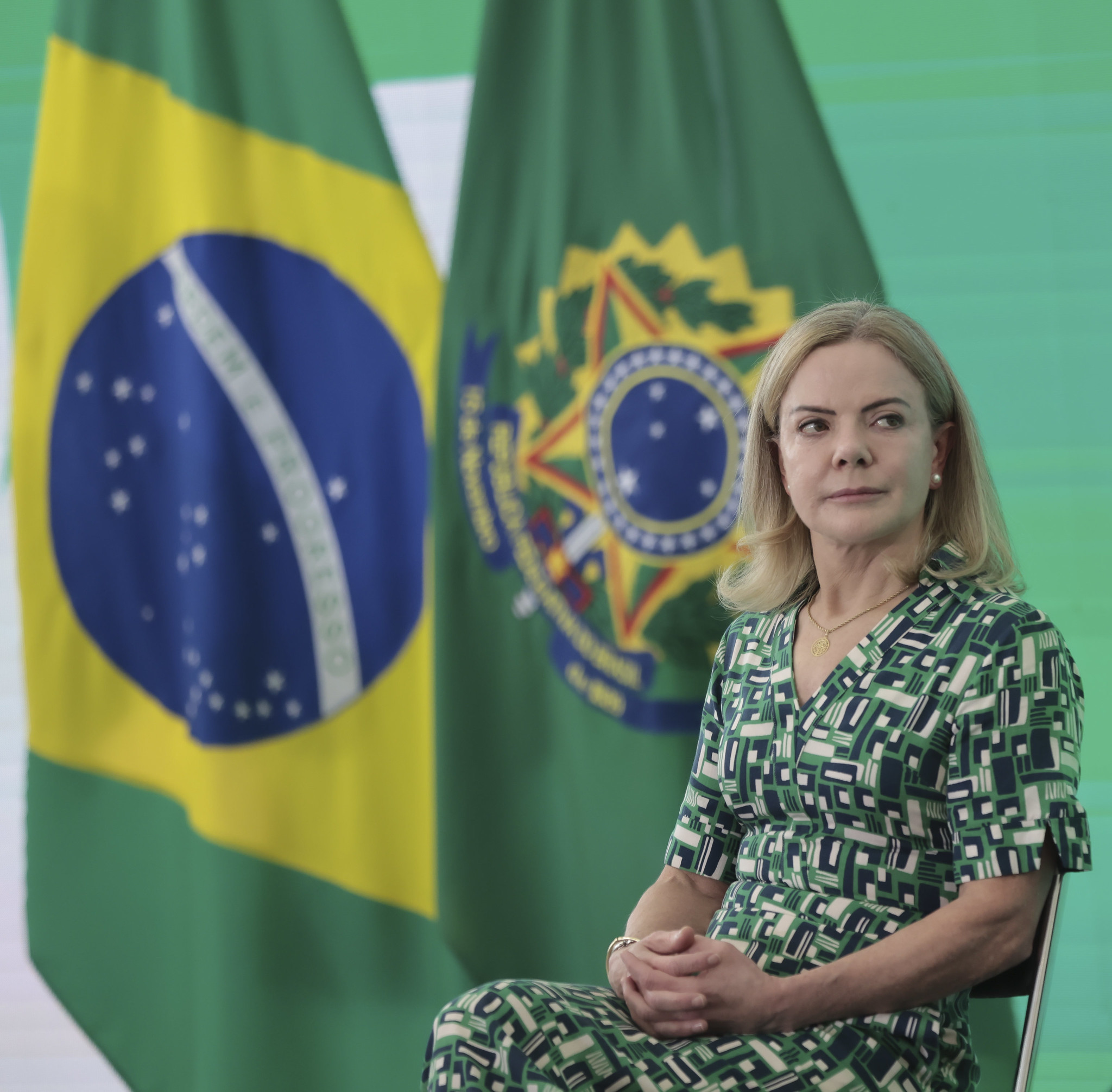 ministra-chefe da Secretaria de Relações Institucionais, Gleisi Hoffmann, sentada, de vestido verde e cabelo solto, olhando para o lado, séria