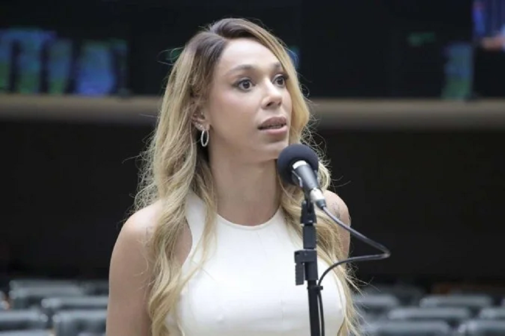 deputada federal Erika Hilton (PSOL-SP) de roupa clara e cabelo solto, falando em microfone