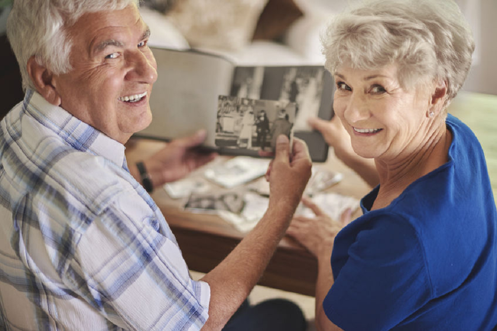 Casal de idosos vendo fotografias e sorrindo olhando para trás