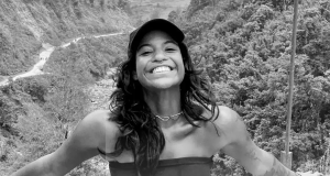 A publicitária Juliana Marins sorrindo para a câmera, de boné e top sem alças, em foto em preto e branco