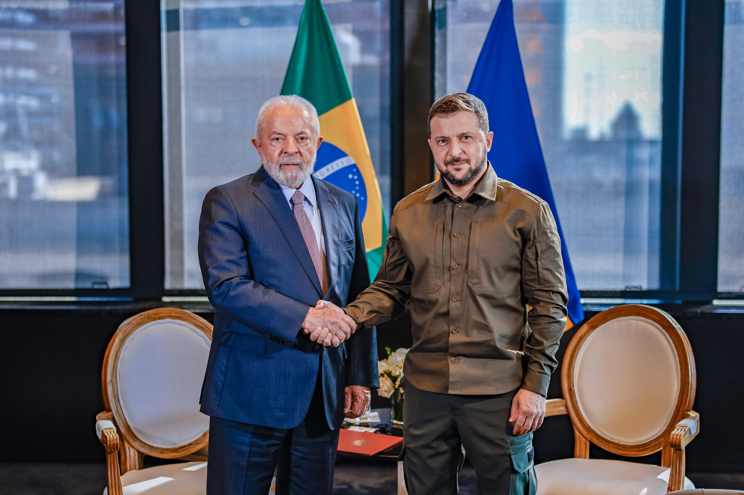 O presidente Lula e o presidente da Ucrânia, Volodymyr Zelensky, em aperto de mãos, posando para foto em pé
