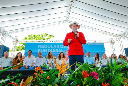 O presidente Luiz Inácio Lula da Silva (PT) de roupa vermelha e chapéu, falando em microfone