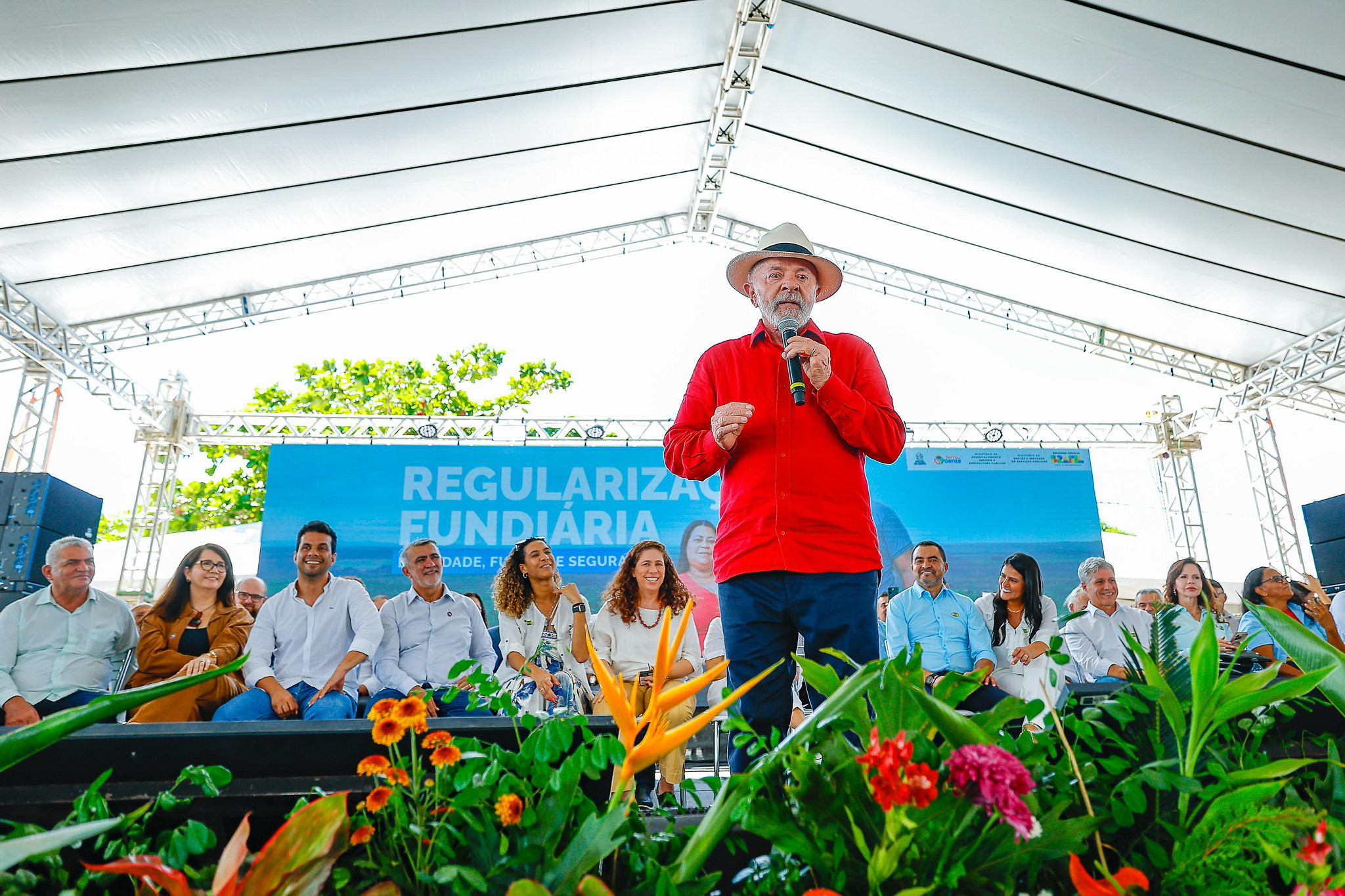 O presidente Luiz Inácio Lula da Silva (PT) de roupa vermelha e chapéu, falando em microfone