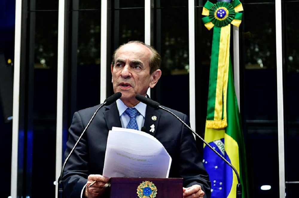 senador Marcelo Castro (MDB-PI) falando em microfone e segurando papel, sério