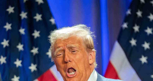 O presidente dos Estados Unidos, Donald Trump, falando com expressão séria, com bandeiras dos EUA no fundo