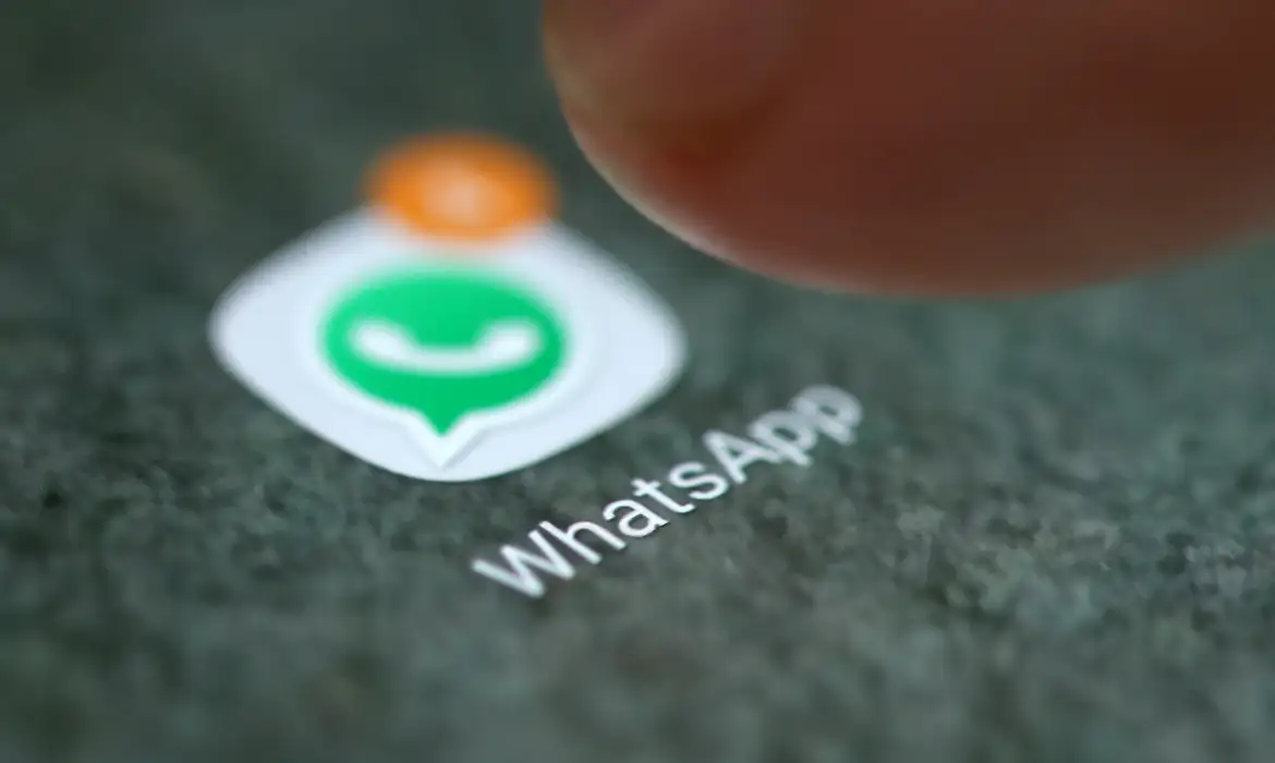 Dedo tocando em ícone do WhatsApp