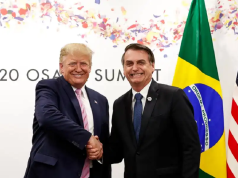 Donald Trump e Jair Bolsonaro em aperto de mãos, sorrindo para a câmera