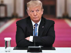 Donald Trump de braços cruzados e expressão séria