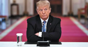 Donald Trump de braços cruzados e expressão séria