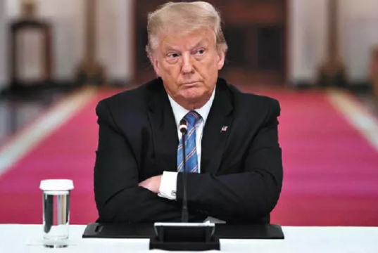 Donald Trump de braços cruzados e expressão séria