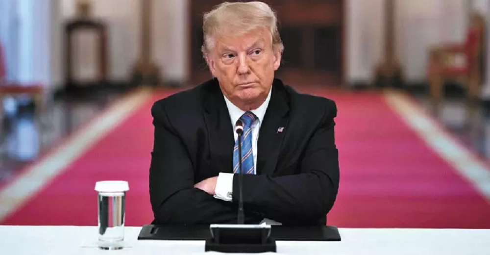 Donald Trump de braços cruzados e expressão séria