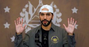 presidente de El Salvador, Nayib Bukele, sério, com as mãos para o alto, de boné para trás