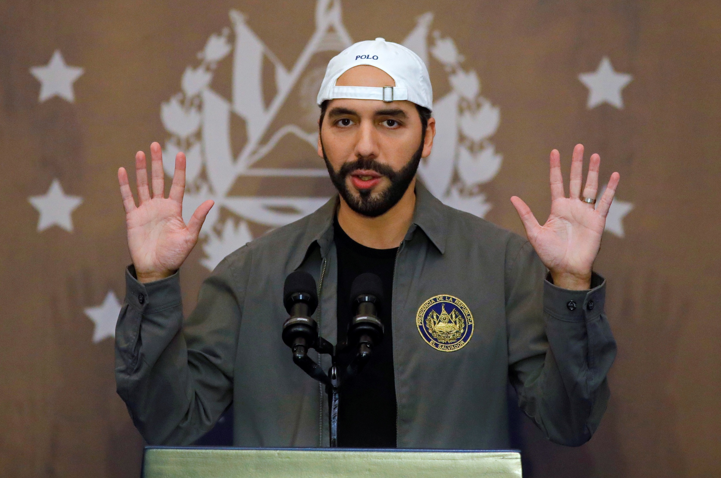 presidente de El Salvador, Nayib Bukele, sério, com as mãos para o alto, de boné para trás