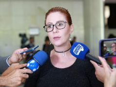deputada federal licenciada Carla Zambelli (PL-SP) falando em microfones, séria, de óculos e cabelo preso