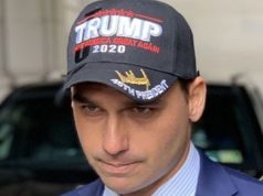 Eduardo Bolsonaro com boné de Trump, sério, em close, sem olhar para a câmera