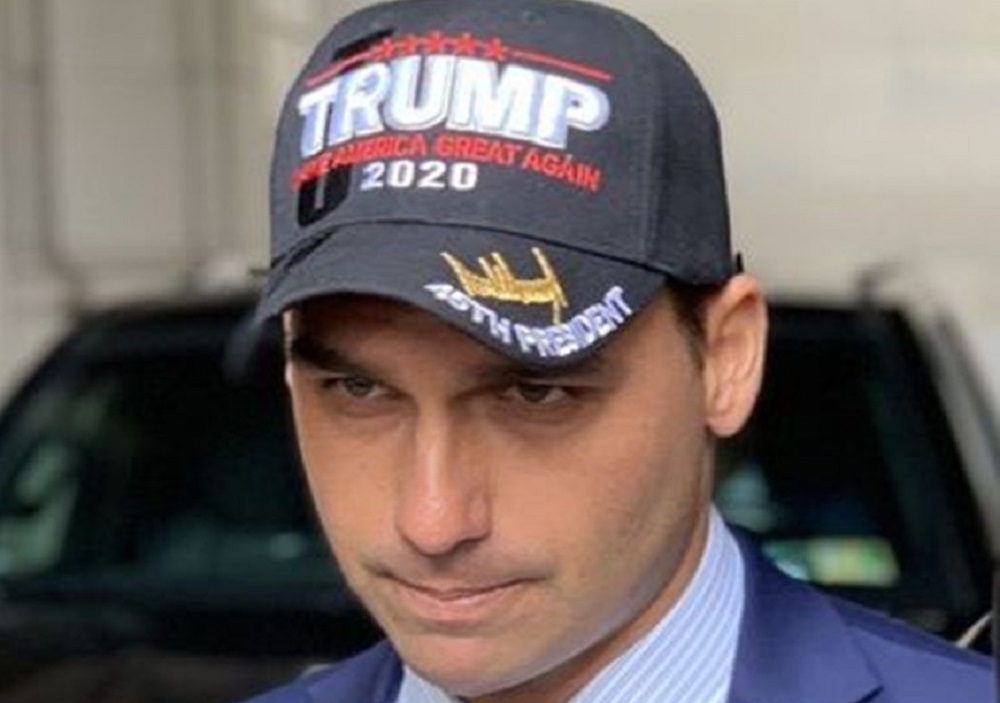 Eduardo Bolsonaro com boné de Trump, sério, em close, sem olhar para a câmera