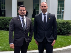 O jornalista Paulo Figueiredo e o deputado federal licenciado Eduardo Bolsonaro (PL) em pé lado a lado, olhando para a câmera