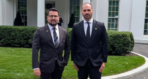 O jornalista Paulo Figueiredo e o deputado federal licenciado Eduardo Bolsonaro (PL) em pé lado a lado, olhando para a câmera