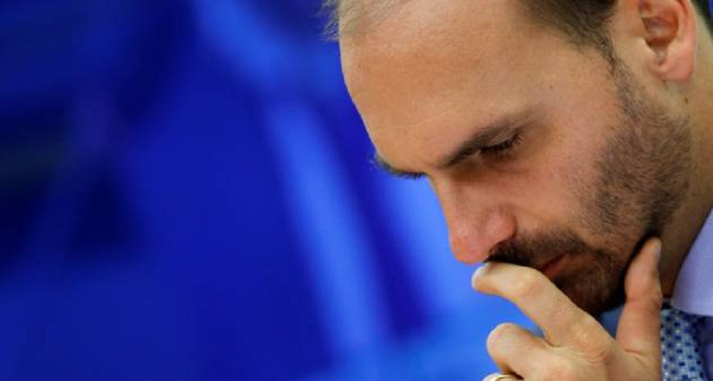 deputado federal licenciado Eduardo Bolsonaro (PL-SP) no canto direito da foto, cabisbaixo, sério, com uma mão na boca