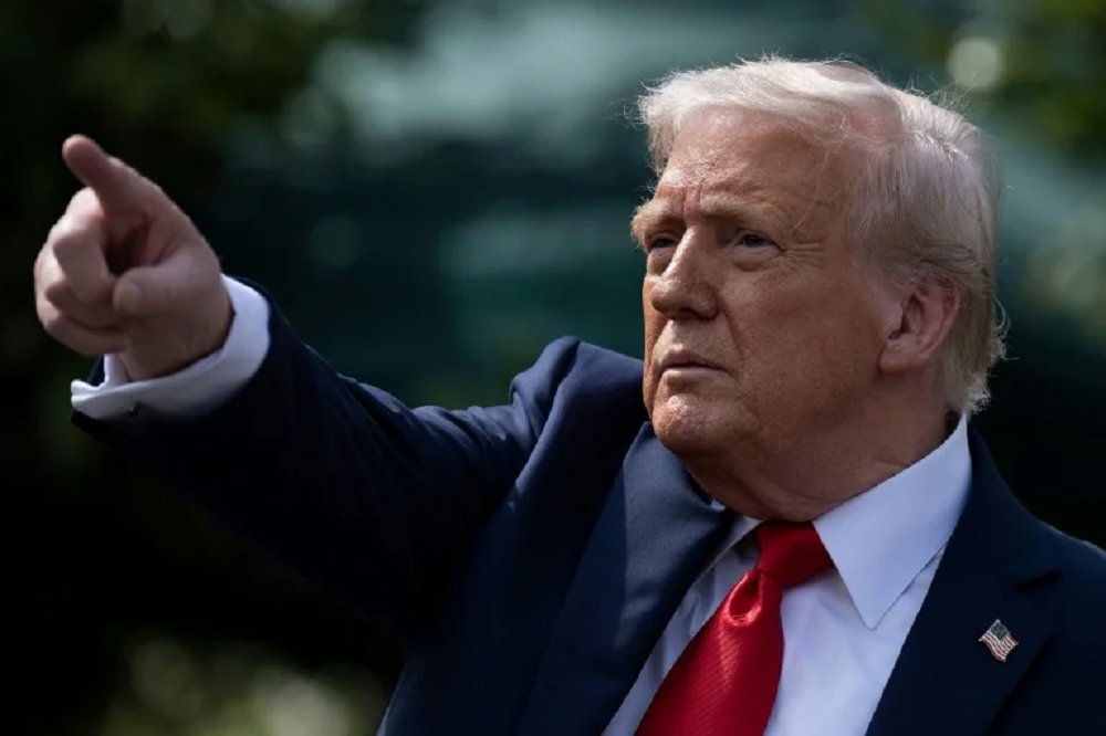 Donald Trump apontando pra frente, sério, de perfil