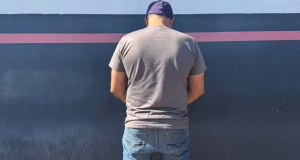 Homem de costas, de boné, em pé