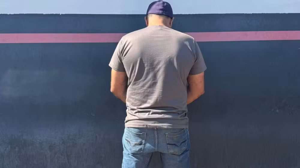 Homem de costas, de boné, em pé