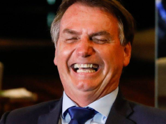 Jair Bolsonaro rindo de olhos fechados, em close
