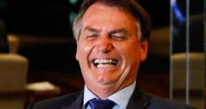Jair Bolsonaro rindo de olhos fechados, em close
