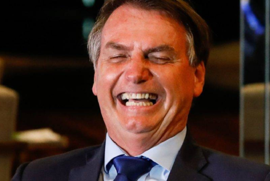 Jair Bolsonaro rindo de olhos fechados, em close