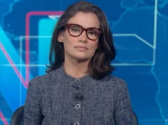 Renata Vasconcellos séria, olhando para a câmera, de óculos e roupa cinza