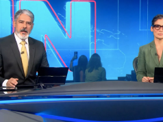 William Bonner e Renata Vasconcellos na bancada do Jornal Nacional, sérios, olhando para a câmera