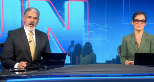 William Bonner e Renata Vasconcellos na bancada do Jornal Nacional, sérios, olhando para a câmera