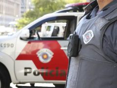 Agente da Polícia Militar de SP, sem mostrar o rosto, perto de carro